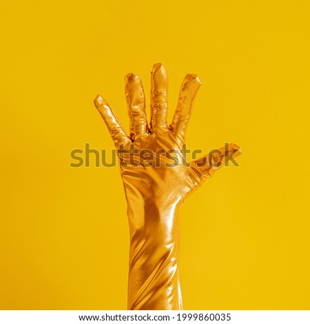 hand with golden glove and number five on yellow sunny summer background. modern summer abstract art