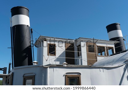 The upper deckhouse of an old ship with two exhaust pipes. Vintage steamship against the blue sky. Royalty-Free Stock Photo #1999866440