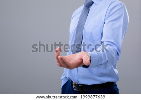 Midsection of caucasian businessman reaching his hand, isolated on grey background. business technology, communication and growth concept.