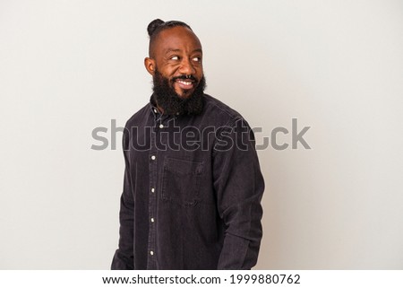 African american man with beard isolated on pink background looks aside smiling, cheerful and pleasant.