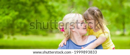 Adult woman and little girl with special needs having fun at summer park. Empty space for text