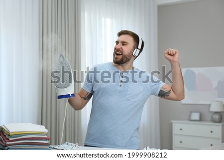 Man listening to music while ironing at home