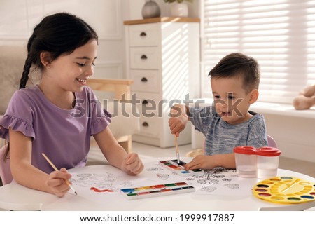 Cute children coloring drawing at table in room