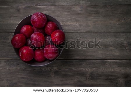 Plum on a dark and light wooden background.