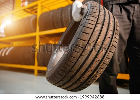 male tire changer In the process of checking the condition of new tires that are in stock to be replaced at a service center or auto repair shop Tire depot for the automobile industry Royalty-Free Stock Photo #1999942688