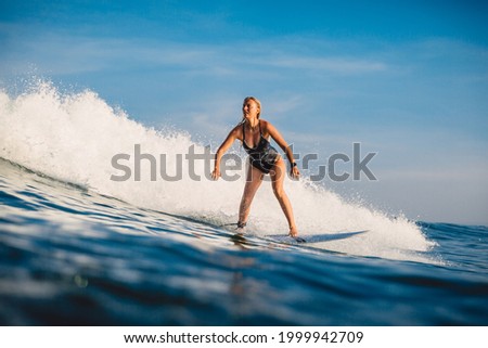 Surfer girl ride on wave at surfboard. Sporty woman in ocean during surfing.