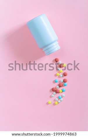 pills and pill bottles on pink background,Round pills of white and orange color poured out on a pink background of white plastic pill bottle. Top view. Medicinal drug. Biohacking concept. 