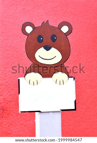 cute teddy bear holding a sign on a red background for children