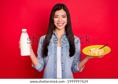 Portrait of attractive cheerful girl eating morning meal drinking kefir good mood isolated over bright red color background