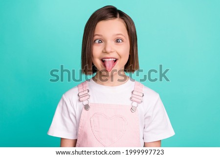Photo of funky happy cheerful young little girl make funny face good mood isolated on teal color background