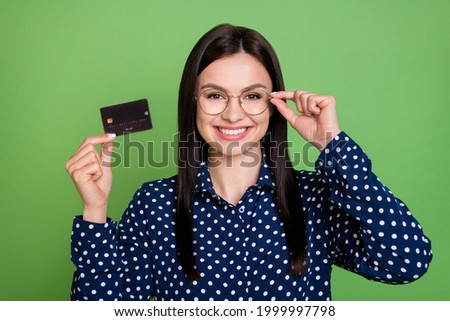 Photo of lovely brunette hairdo young lady show card wear spectacles blue shirt isolated on green color background