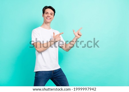 Photo of hooray brunet hairdo young guy point empty space wear white t-shirt isolated on vibrant teal color background