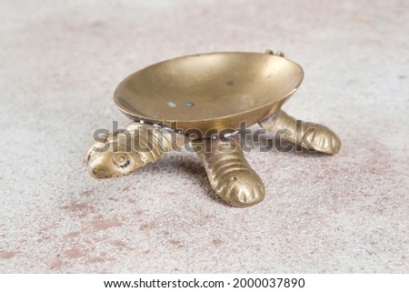 Old brass turtle ashtray on concrete background. Copy space and photography props.