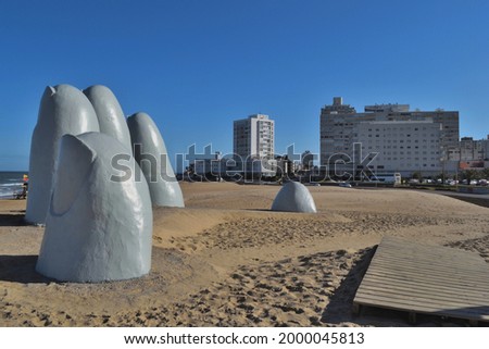 Photography of The Hand in the beach La Brava, Punta del Este City, Uruguay and some buildings behind Royalty-Free Stock Photo #2000045813