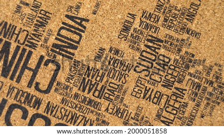 Cork board. Image of countries. Black text. Country names. View from above. Creativity. Art object. Politics. World map. Office object. View from above. Rotation. Close-up.