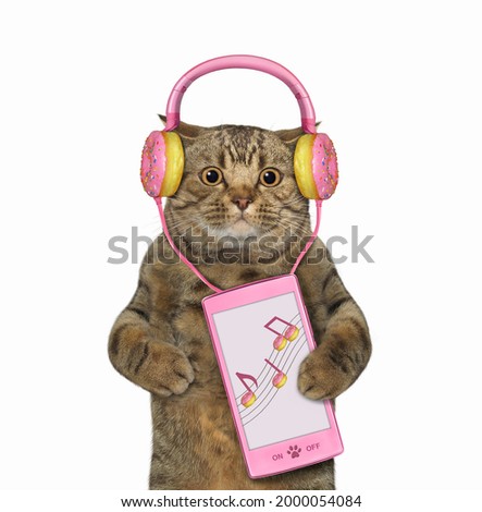 A beige cat in pink donut earphones holds a smartphone. White background. Isolated.