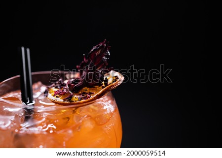 close up of orange aperol spritz lychee cocktail in glass on black background