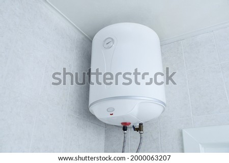 White electric water heater boiler on the wall in the bathroom. Royalty-Free Stock Photo #2000063207