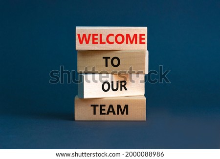 Welcome to our team symbol. Wooden blocks with words 'Welcome to our team' on beautiful grey background. Businessman hand. Business and welcome to our team concept. Copy space.