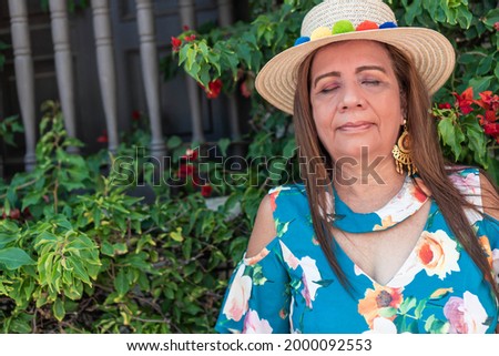 Mature woman with her eyes closed while taking a moment to herself.