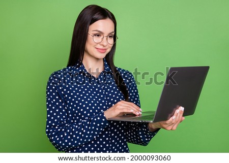 Photo of programmer girl hold netbook look screen wear specs dotted blouse isolated on green color background