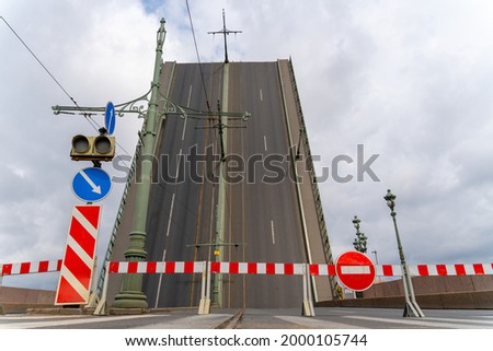 Raised span of bascule Trinity bridge across the Neva in Saint Petersburg, Russia. Movable bridge is blocked by a barrier and warning signs due to repairs.