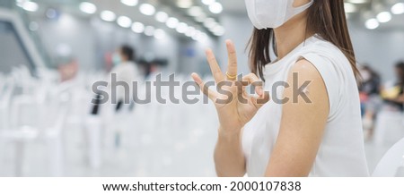 Happy woman showing her arm with bandage and giving ok hand sign after receiving vaccine. Vaccination, immunization, inoculation and Coronavirus ( Covid-19 ) pandemic