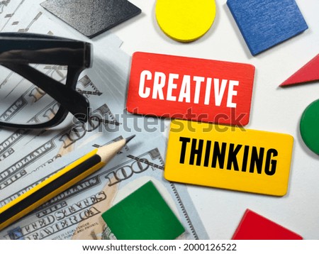 Education concept.Colorful wooden board with text CREATIVE THINKING with fake money,pencil and glasses on white background.
