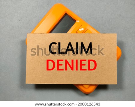 Text CLAIM DENIED on brown card with calculator on gray background.