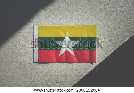 Myanmar flag sticking on the wall with dark tone. The Myanmar national flag consists of three equal horizontal stripes with different colors.