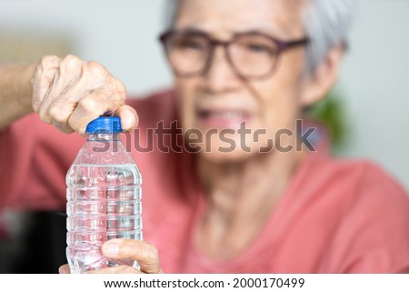 Trouble opening the bottle of drinking water in the elderly age,life problem,senior woman with numbness and weakness of hands and fingers muscle,difficulty in turning or unscrewing cap of water bottle