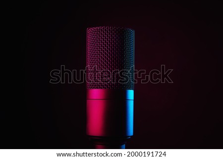 Studio microphone on dark background with copy space. Black professional condencer microphone with neon light. Podcast recording Royalty-Free Stock Photo #2000191724
