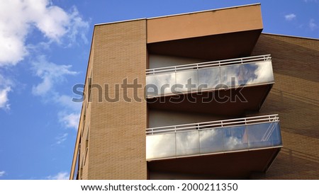 glass balconies on brick facade against the sky