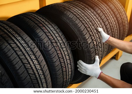 Close to the hands of a tire changer in Large warehouse of car tires, rack with customer car tires in warehouse of a tire dealer Royalty-Free Stock Photo #2000230451