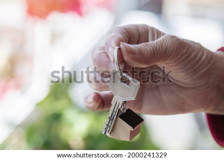 hand holding house keychain and keys, mortgage and real estate concept