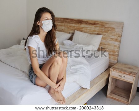 woman wearing medical mask on vacation sitting on bed isolation 