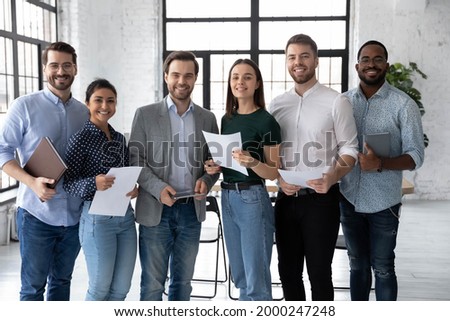Portrait of happy diverse group of interns or students and corporate teacher after successfully passes exam. Multi ethnic business team of employees holding paper documents, looking at camera, smiling Royalty-Free Stock Photo #2000247248
