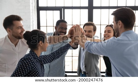 Business team of happy motivated staff employees giving joined hands high fives. Excited work group celebrating corporate financial success, good sales result, successful teamwork and achievement Royalty-Free Stock Photo #2000247476