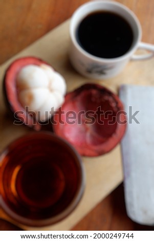 Blur photo of fresh mangosteen fruit and coffee on wooden table background