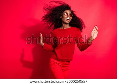 Portrait of attractive amazed cheerful girl having fun wind blowing isolated over bright red color background