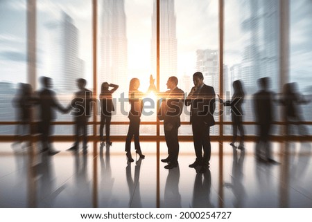 Successful businesspeople hi-fiving in blurry office interior with sunlight. Success and work ethics concept Royalty-Free Stock Photo #2000254727