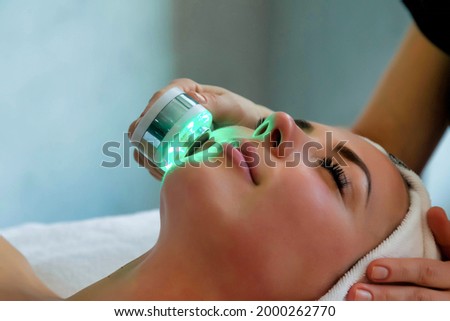 Beautician doing led light therapy to woman in SPA salon, facial phototherapy for skin pore cleaning. Anti-aging treatments and photo rejuvenation procedure. Lady getting face therapy in SPA resort Royalty-Free Stock Photo #2000262770