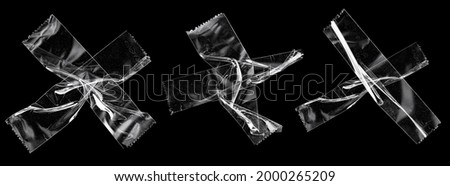 transparent sticky tapes forming the letter x or overlapping each other on black background, crumpled plastic snips, poster design overlays.