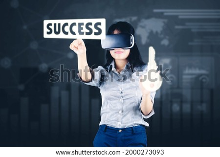 Young businesswoman using a VR glasses to touching success word and key symbol while standing with virtual screen background