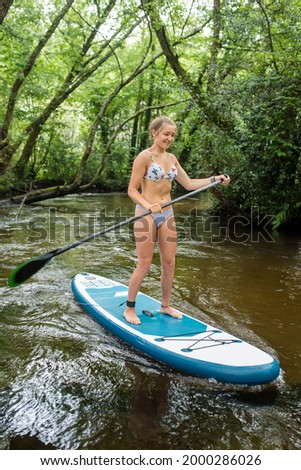 beautiful young woman paddle boarding in a wonderful river 