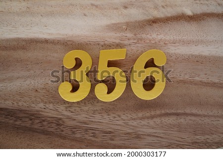 Gold Arabic numerals 356 on a dark brown to off-white wood pattern background.
