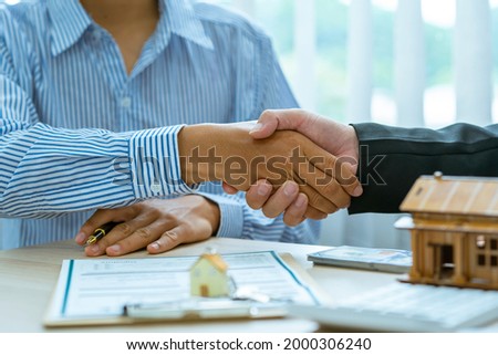 Real estate broker and client sign contract insurance agreement document. Business meeting concept, home loan insurance.