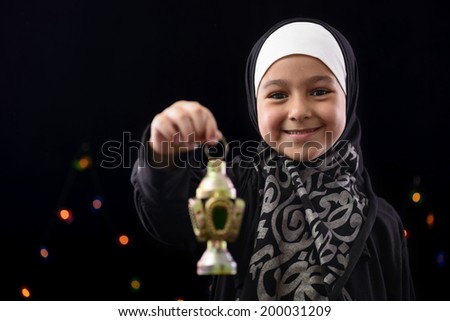 Happy Muslim Girl Celebrating Ramadan on Defocused Night Lights Background Royalty-Free Stock Photo #200031209