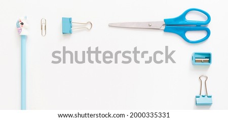 Top view of modern white blue office desktop with school supplies and stationery on table around empty space for text. Back to school concept flat lay with mockup