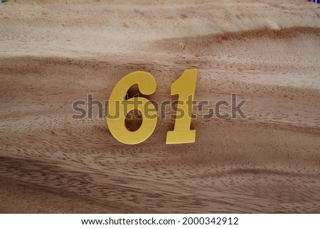 Gold Arabic numerals 61 on a dark brown to off-white wood pattern background.